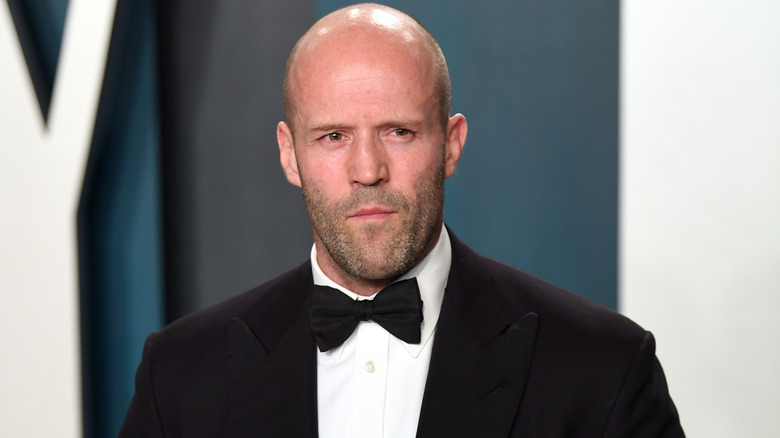 Jason Statham wearing a tuxedo with a serious expression