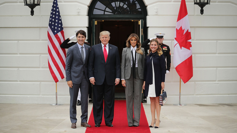 Melania Trump wearing an undone tie and a pantsuit alongside President Trump and the Trudeaus