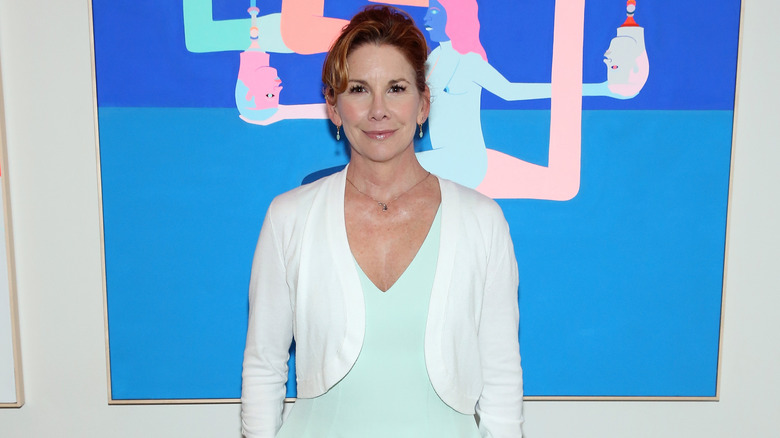 Melissa Gilbert posing in a white cardigan.