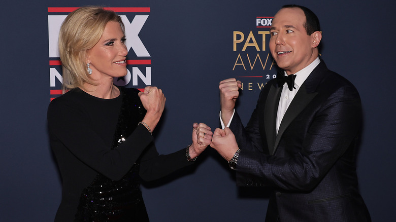 Laura Ingraham and Raymond Arroyo play-fighting on the red carpet.