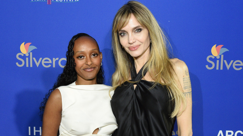 Zahara Jolie wearing a white dress and Angelina Jolie wearing a black dress.