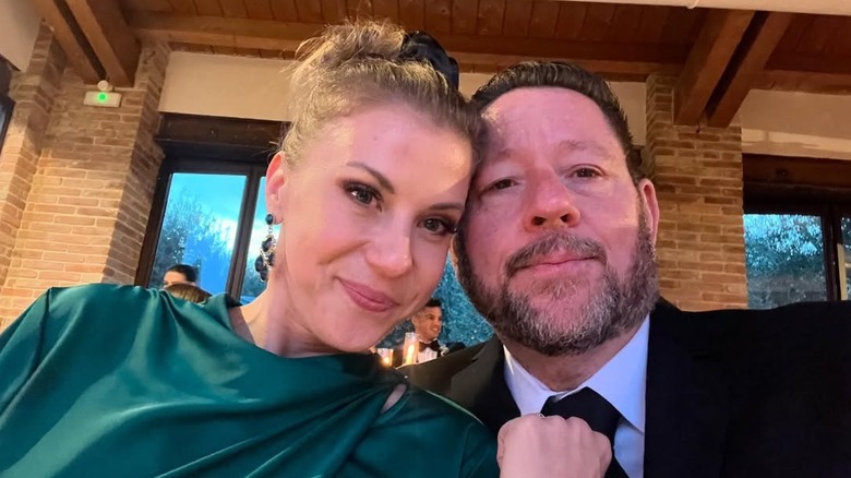 Jodie Sweetin wearing a green dress and posing with Mescal Wasilewski, who wears a black suit and tie.