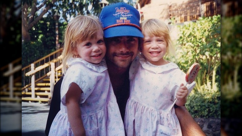 John Stamos crouching down with Olsen twins