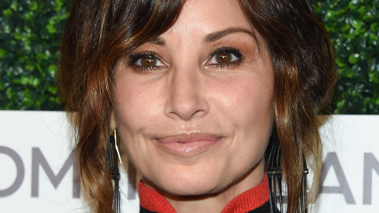 Gina Gershon poses in a black and red garment