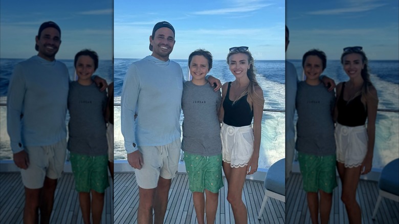 The Rancic family flashes wide smiles while posing against an ocean backdrop