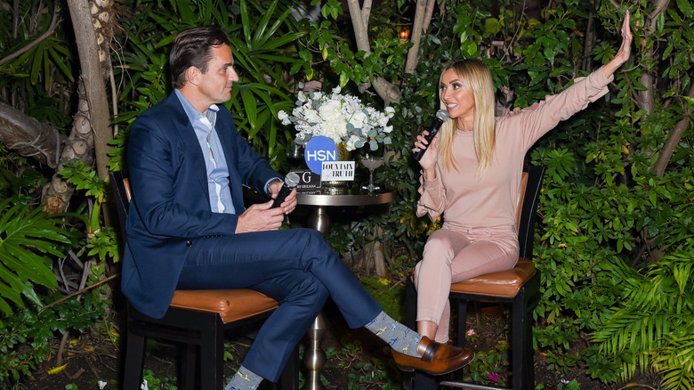 Giuliana and Bill Rancic sitting together and chatting animatedly at an event