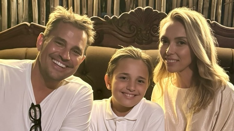 Bill, Duke and Giuliana Rancic sitting on a couch smiling in white shirts