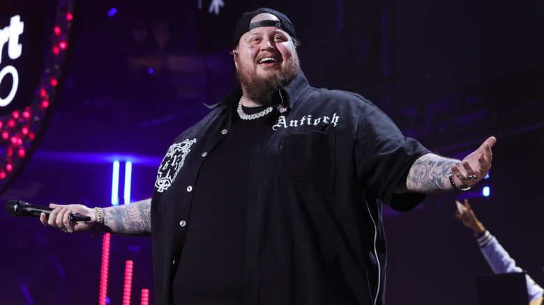 Jelly Roll performing onstage with his arms spread