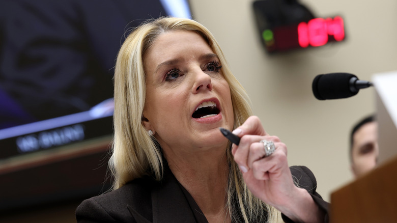 Pam Bondi yells into microphone while holding pen