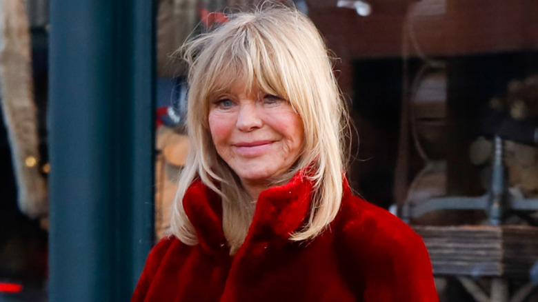 Goldie Hawn wearing a red coat outdoors in Aspen