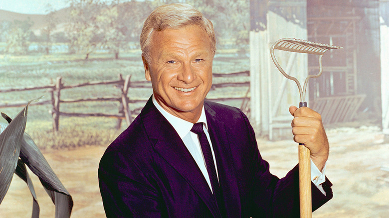 Eddie Albert holding a rake in a publicity photo for "Green Acres"