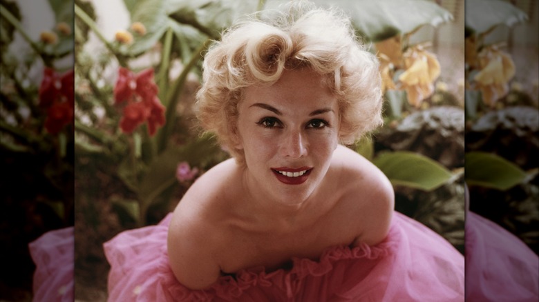 Eva Gabor posing for a picture in a strapless pink tulle dress in the 1950s.