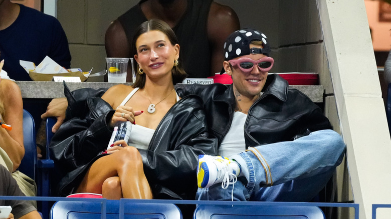 Justin Bieber seated with his arm around Hailey Bieber at a game.