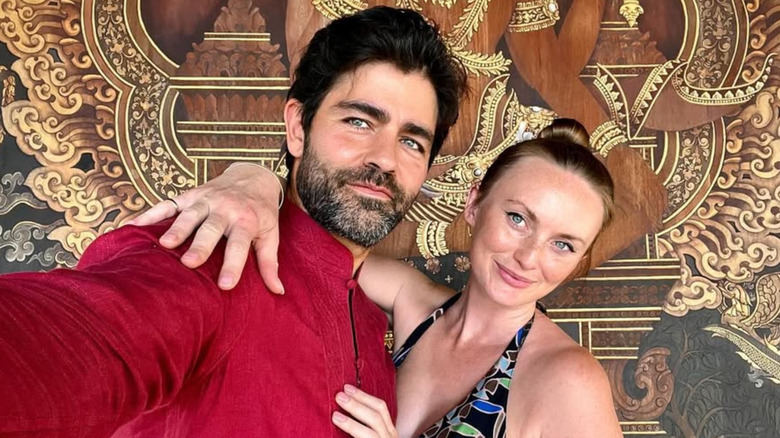 Adrian Grenier taking a selfie with wife Jordan Grenier, who has her arm around his shoulders.