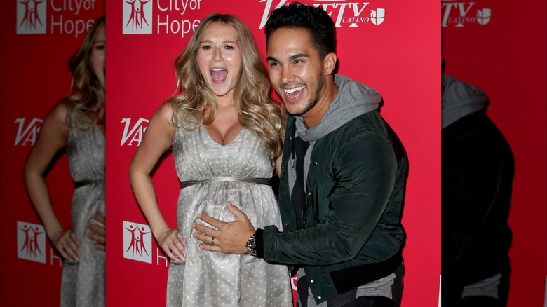 Alexa PenaVega posing with her hubby as he holds her belly
