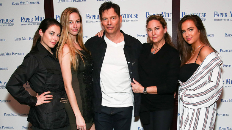 Harry Connick Jr. posing between his wife, Jill Goodacre, and their three daughters.