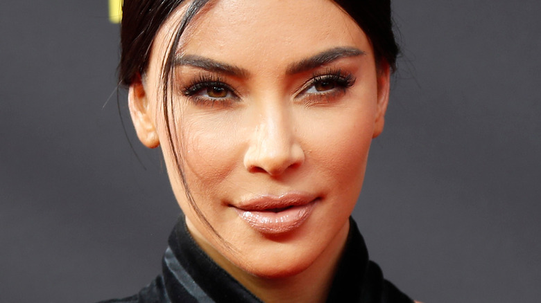 Kim Kardashian poses in a black outfit with slight smile