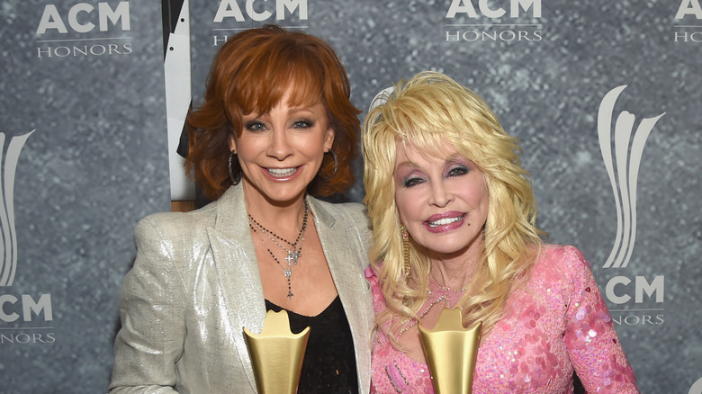 Reba McEntire and Dolly Parton posing with their trophies