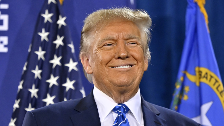 Donald Trump smiling in front of American flag