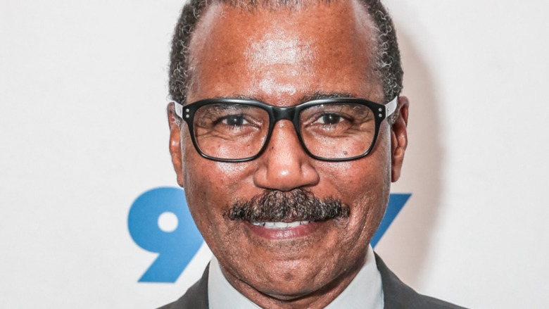 Bill Whitaker smiling wearing thick-rimmed glasses