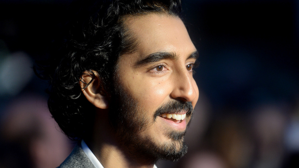 Dev Patel smiles as he poses at an event