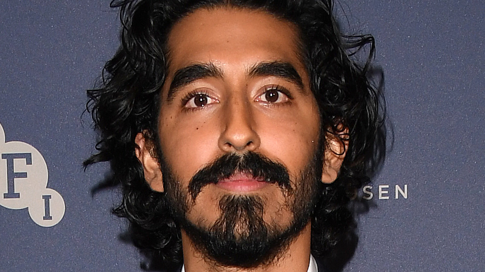 Dev Patel looks serious as he poses at an event