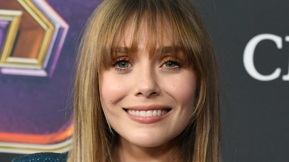 Elizabeth Olsen smiles while posing on the red carpet