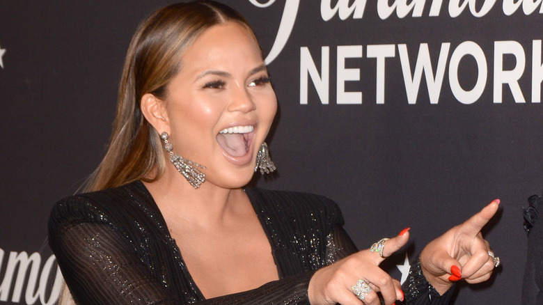 Chrissy Teigen pointing her fingers on the red carpet