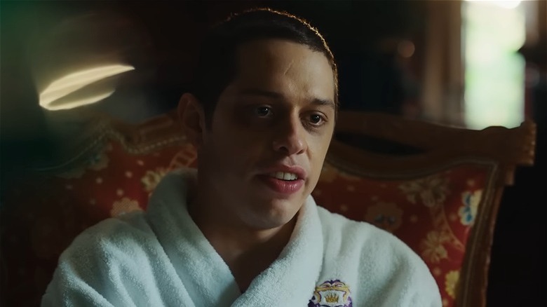 Pete Davidson in a bathrobe, seated