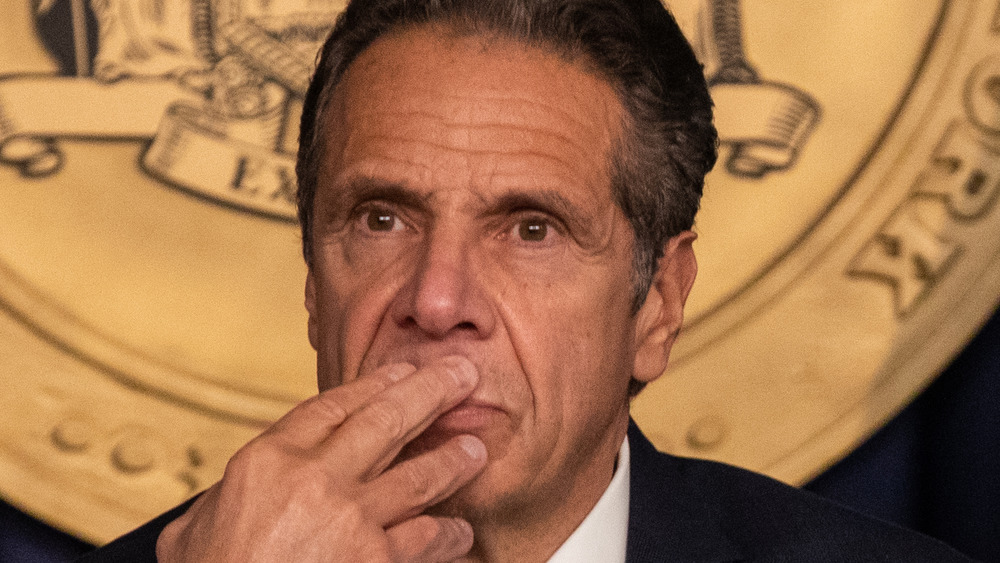 Andrew Cuomo looking on with hand on his mouth.