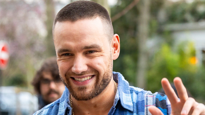 Liam Payne smiling and waving outdoors