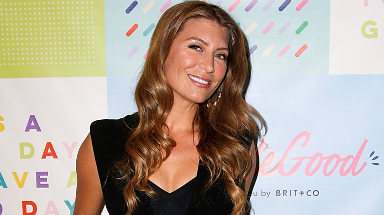 Genevieve Gorder posing in front of a multi-colored background