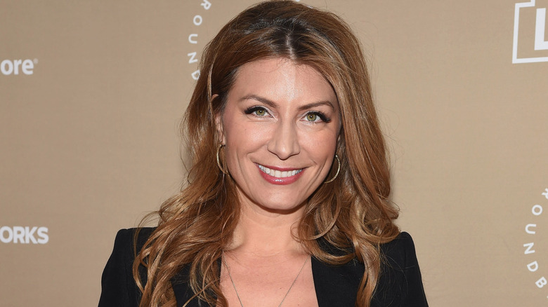 Genevieve Gorder posing in front of a blue background