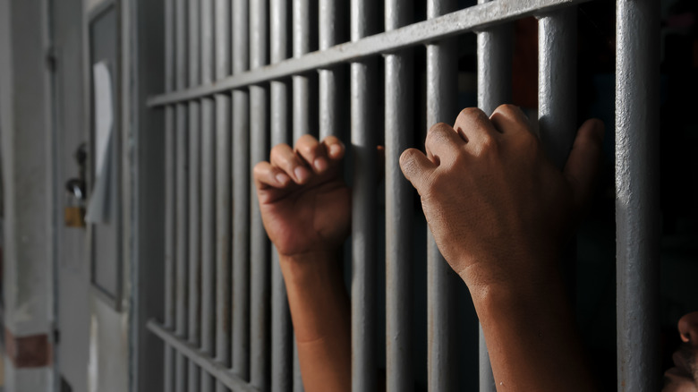 The hands of a prisoner behind bars