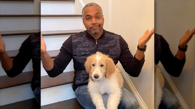 Mike Jackson shrugs with dog in his lap