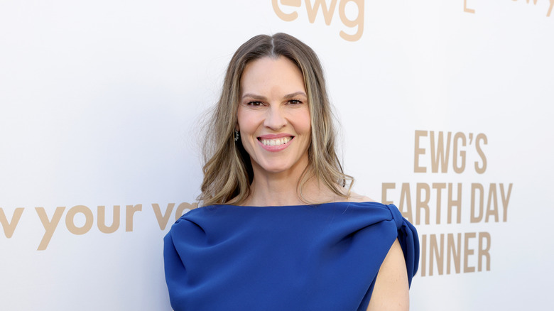 Hilary Swank smiling while posing on the red carpet in a blue dress