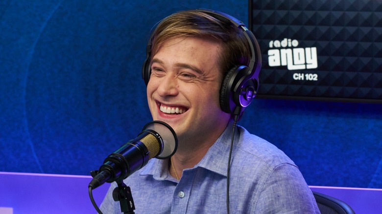 Tyler Henry lights up with a cheerful grin while wearing a pair of headsets