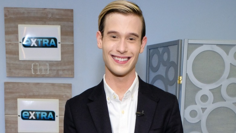 Wearing a black and white shirt-suit combo, Tyler Henry smiles ear-to-ear