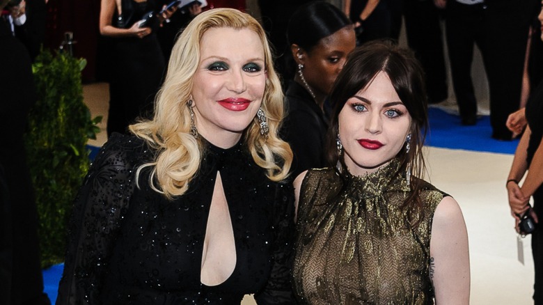 Courtney Love leans toward Frances Bean Cobain, who is giving the camera a cold stare.