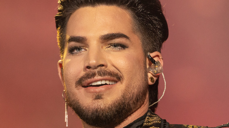 Adam Lambert smiles on stage