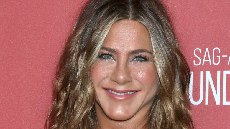 Jennifer Aniston with hair down smiling at camera on red carpet