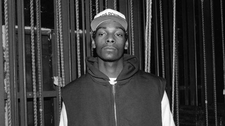 Snoop Dogg wears a baseball hat and sleeveless hoodie