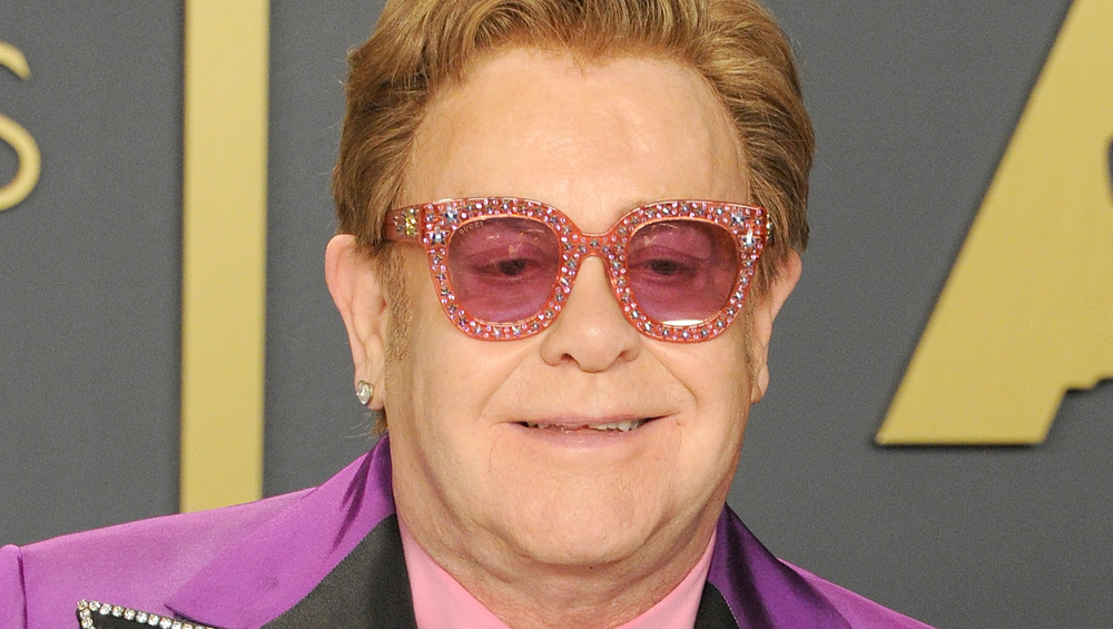 Elton Johns, smiling, Oscars red carpet, 2020, wearing sparkly pink glasses, purple suit