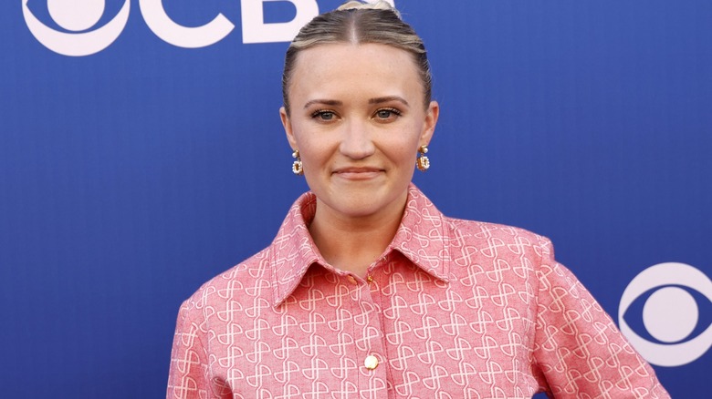 Wearing a collared pink number, Emily Osment makes a face as she looks away from the camera.
