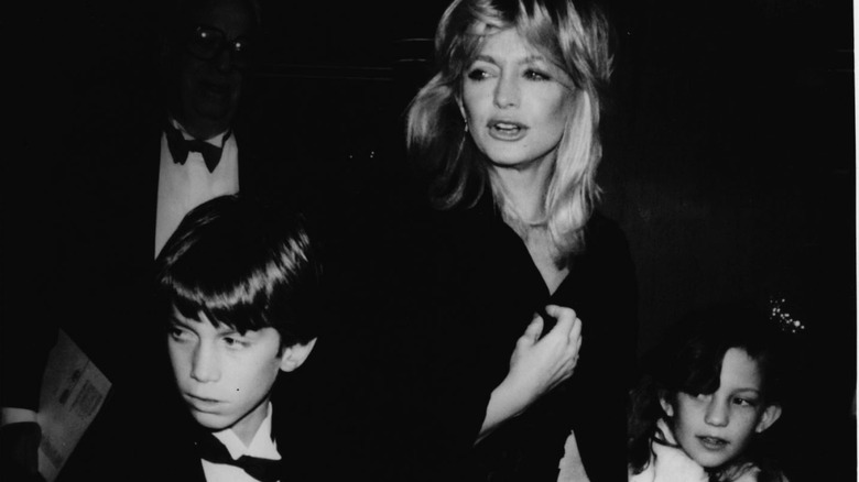 Black and white photo of Goldie Hawn walking with kids Oliver and Kate Hudson