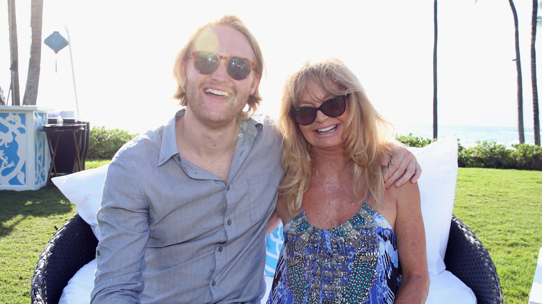 Wyatt Russell posing with Goldie Hawn, with both wearing sunglasses