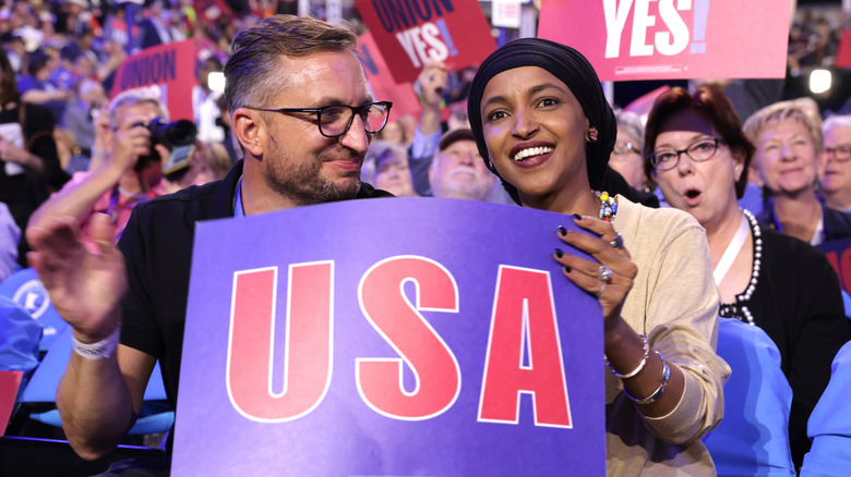 Ilhan Omar smiling while Tim Mynett looks at her