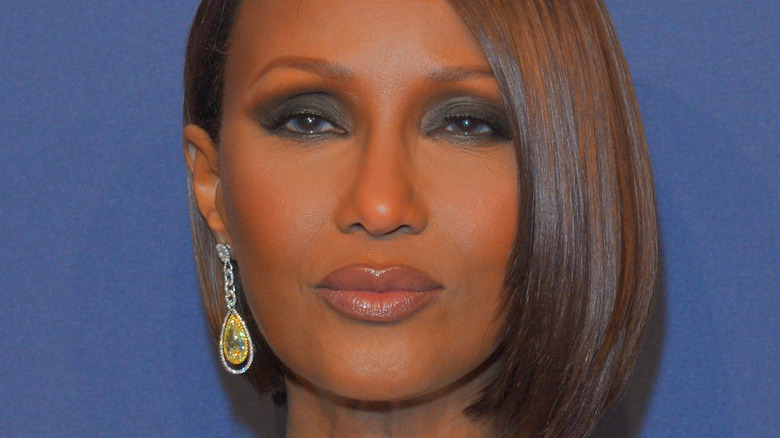 Iman poses with short bob and dangling earring