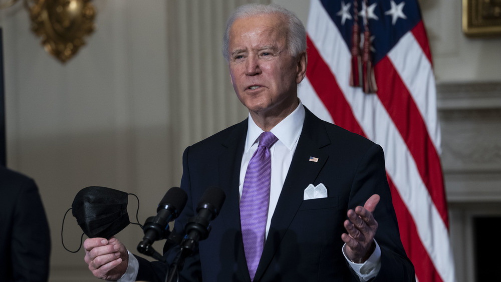 Joe Biden holding a face mask while speaking with reporters