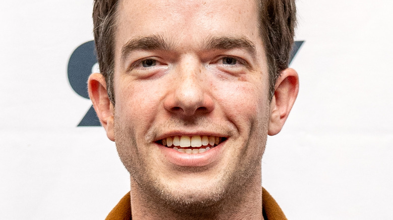 John Mulaney smiling and looking into the camera